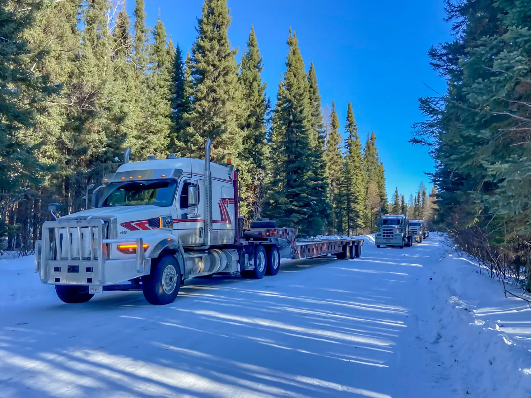 three transport trucks driving down a snow covered road